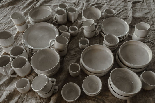 A beautifully styled coastal Japandi dining table with raw linen, stoneware plates, and soft natural light.